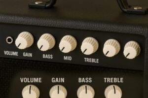 Close-up of amp knobs labeled (volume, gain, bass, mid, treble)