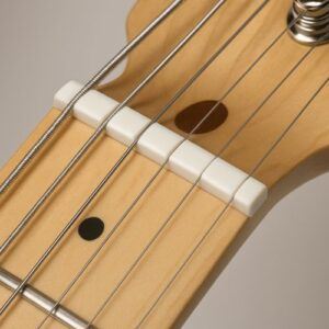 Modern bright-white TUSQ nut close-up on maple neck, smooth uniform finish.