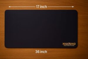 Warm close-up of a MusicNomad guitar work mat laid on a wooden bench, showing the full 17" × 36" surface with rounded corners and a dark, non-slip texture.