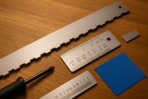 Warm close-up of two unfinished guitar bodies on a luthier workbench: a bolt-on neck pocket with screws and plate laid out beside it, and a neck-through body showing continuous wood grain. Calipers, ruler, and small straightedge arranged neatly under soft workshop lighting.