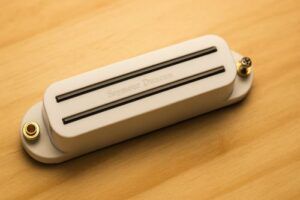 Close-up of a Seymour Duncan SHR-1b Hot Rails Strat bridge humbucker in cream housing on a wooden background.