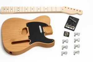 DIY Tele-style electric guitar kit with an unfinished alder body, maple bolt-on neck, black pickguard, chrome hardware, and electronics laid out on a white background.