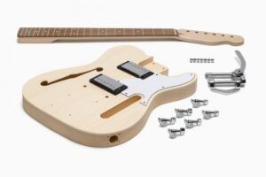 Semi-hollow Tele-style DIY guitar kit with unfinished body, maple neck, dual pickups, hardware, and vibrato trem system arranged on a white background.